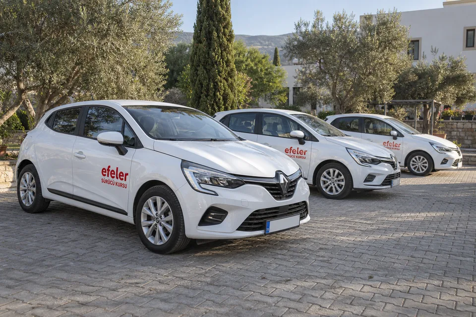 Yan yana park edilmiş Efeler logolu beyaz eğitim otomobilleri